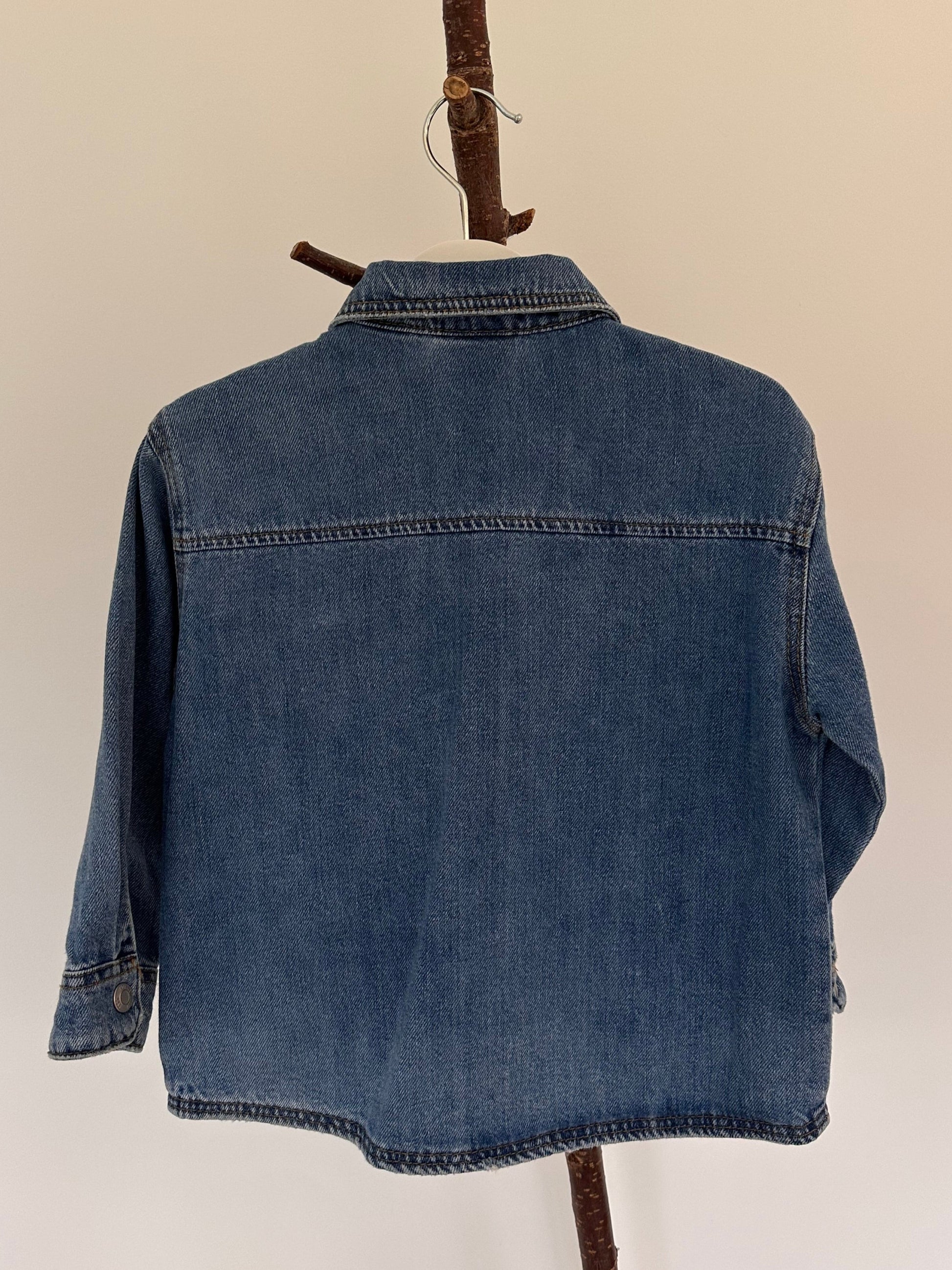 Blue denim shirt on a wooden stick against a beige background