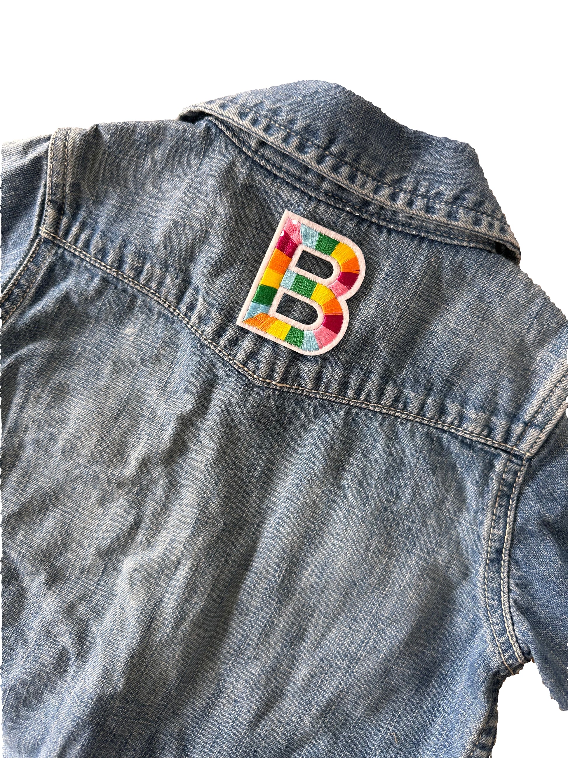 Denim jacket with a colorful 'B' patch on a white background