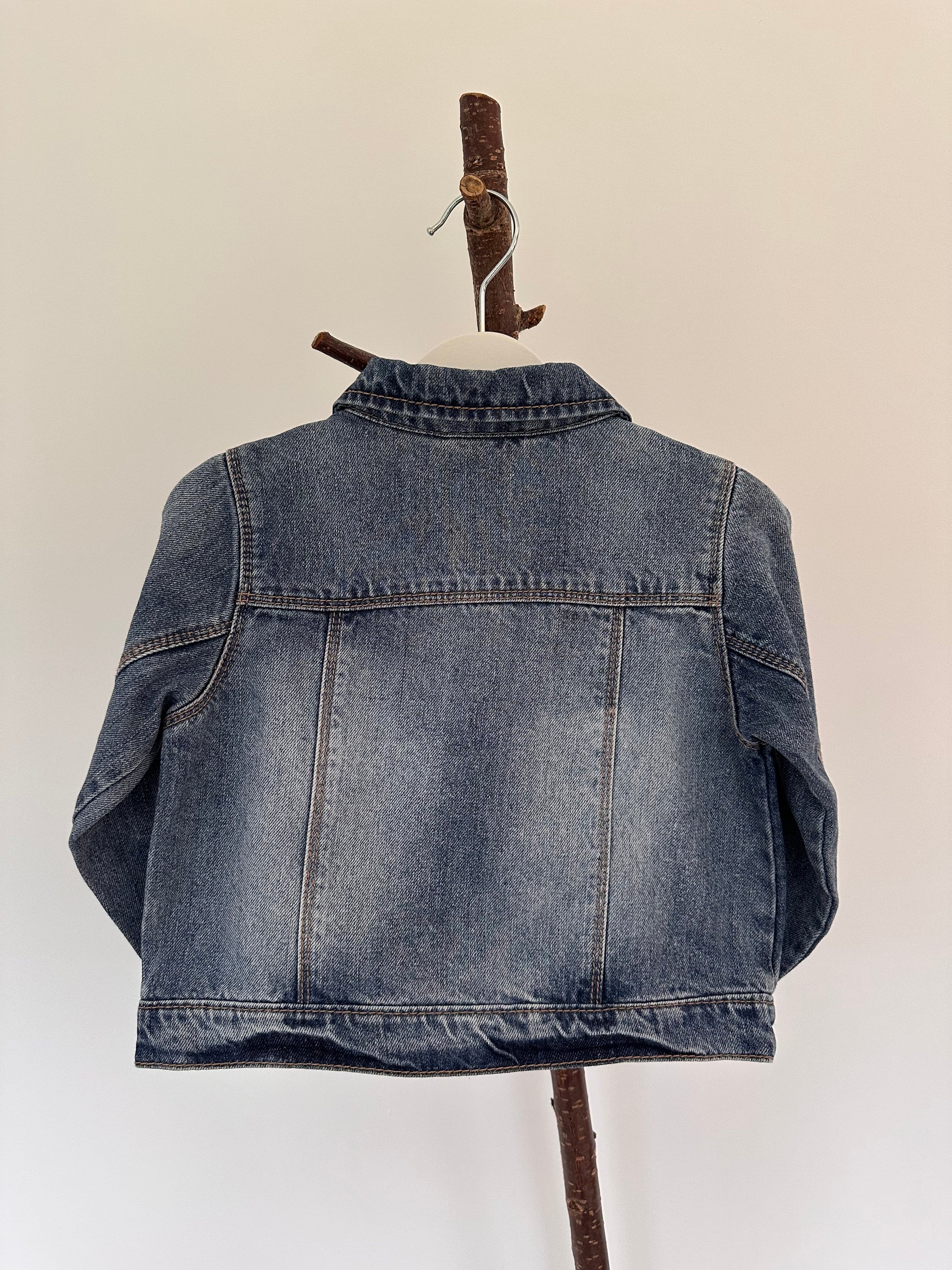 Folded blue denim jacket on a beige background