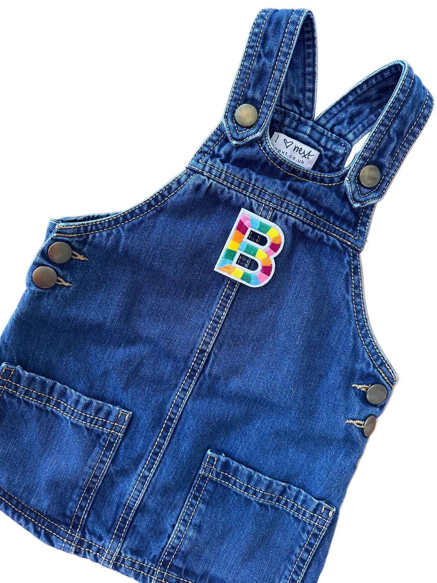 Blue denim romper with a colorful patch on a wooden surface