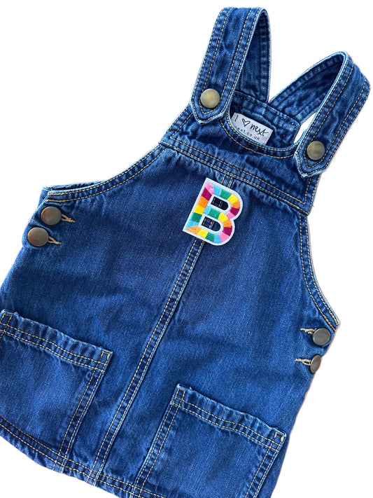 Blue denim romper with a colorful patch on a wooden surface