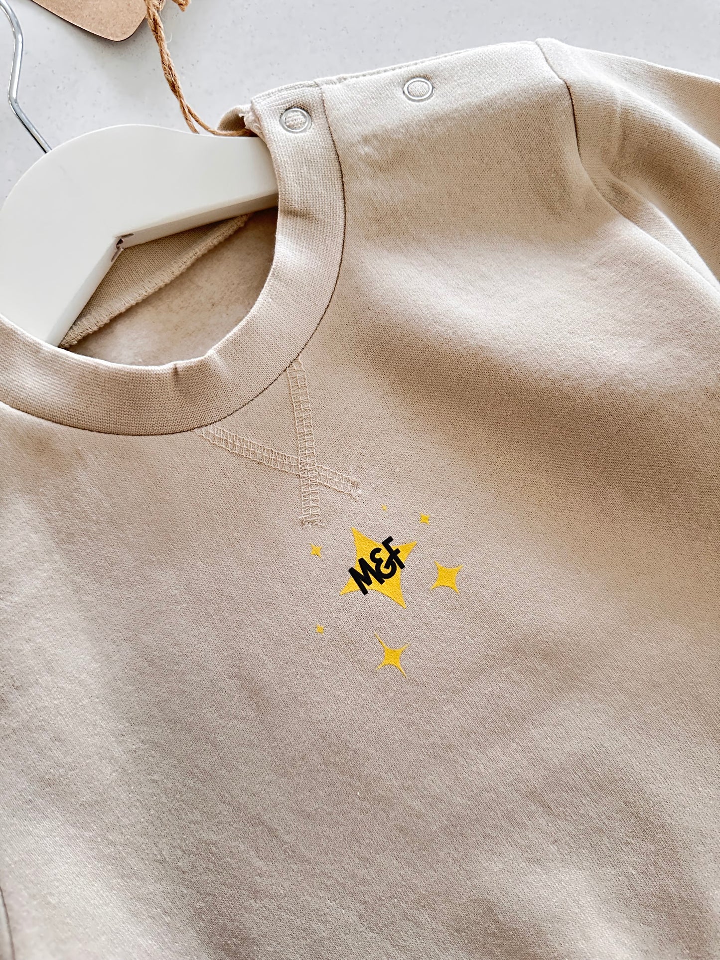 Beige fabric with a small yellow logo on a light gray background