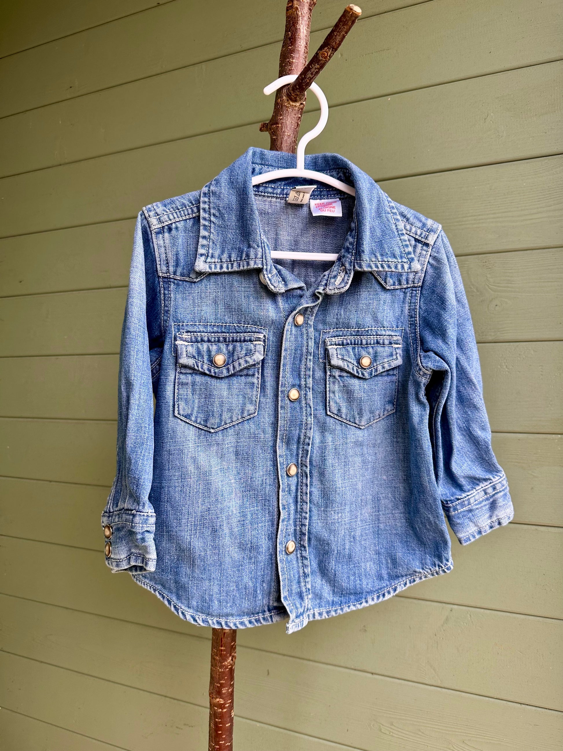 Blue denim shirt on a hanger against a wooden wall