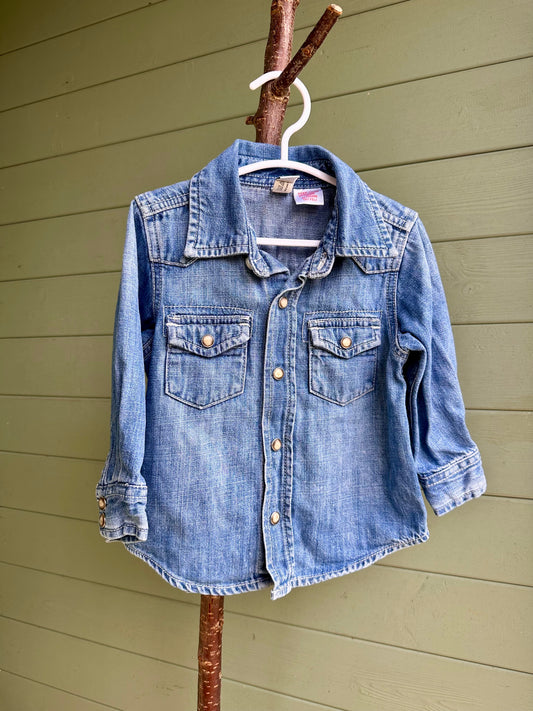 Blue denim shirt on a hanger against a wooden wall